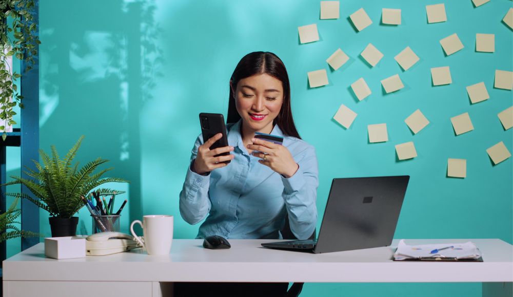 Businesswoman using Google Ads on her phone to make purchases online, highlighting how local businesses can leverage Google Ads for increased sales.