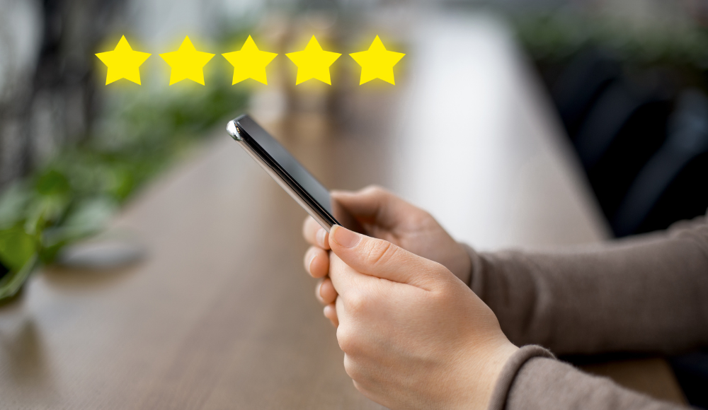 A person holding a smartphone displaying 5-star reviews, symbolizing the importance of customer feedback and online reviews.